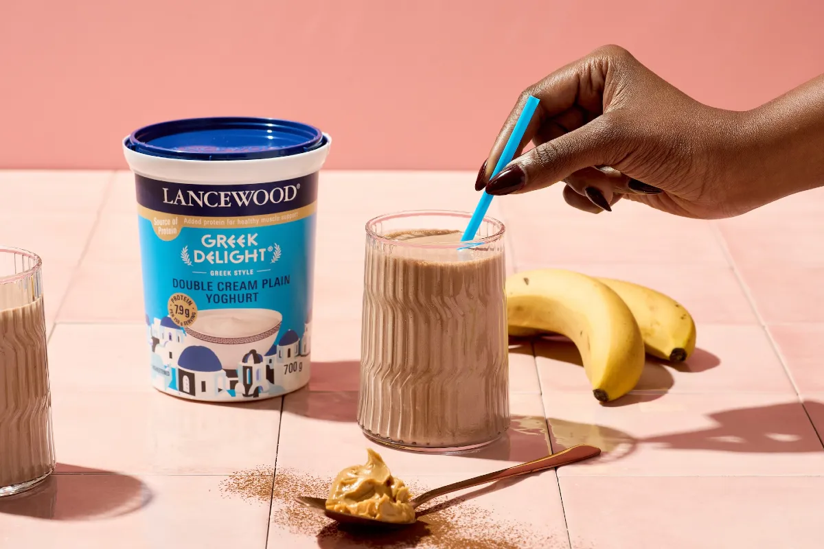 High Protein chocolate smoothie with LANCEWOOD Greek Delight® yoghurt on a table with bananas