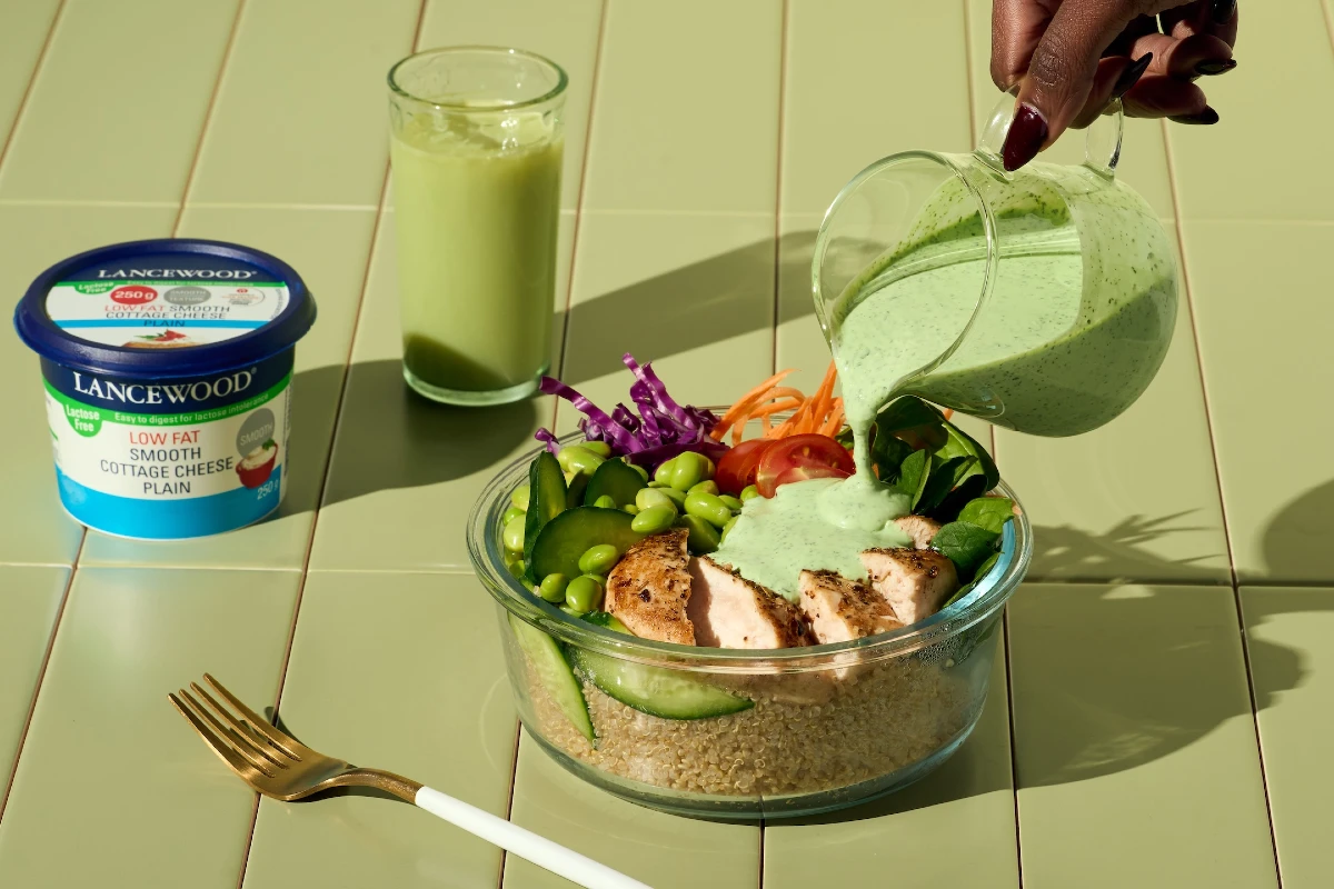 High protein bowl made with LANCEWOOD® cottage cheese, and dressing being poured over food