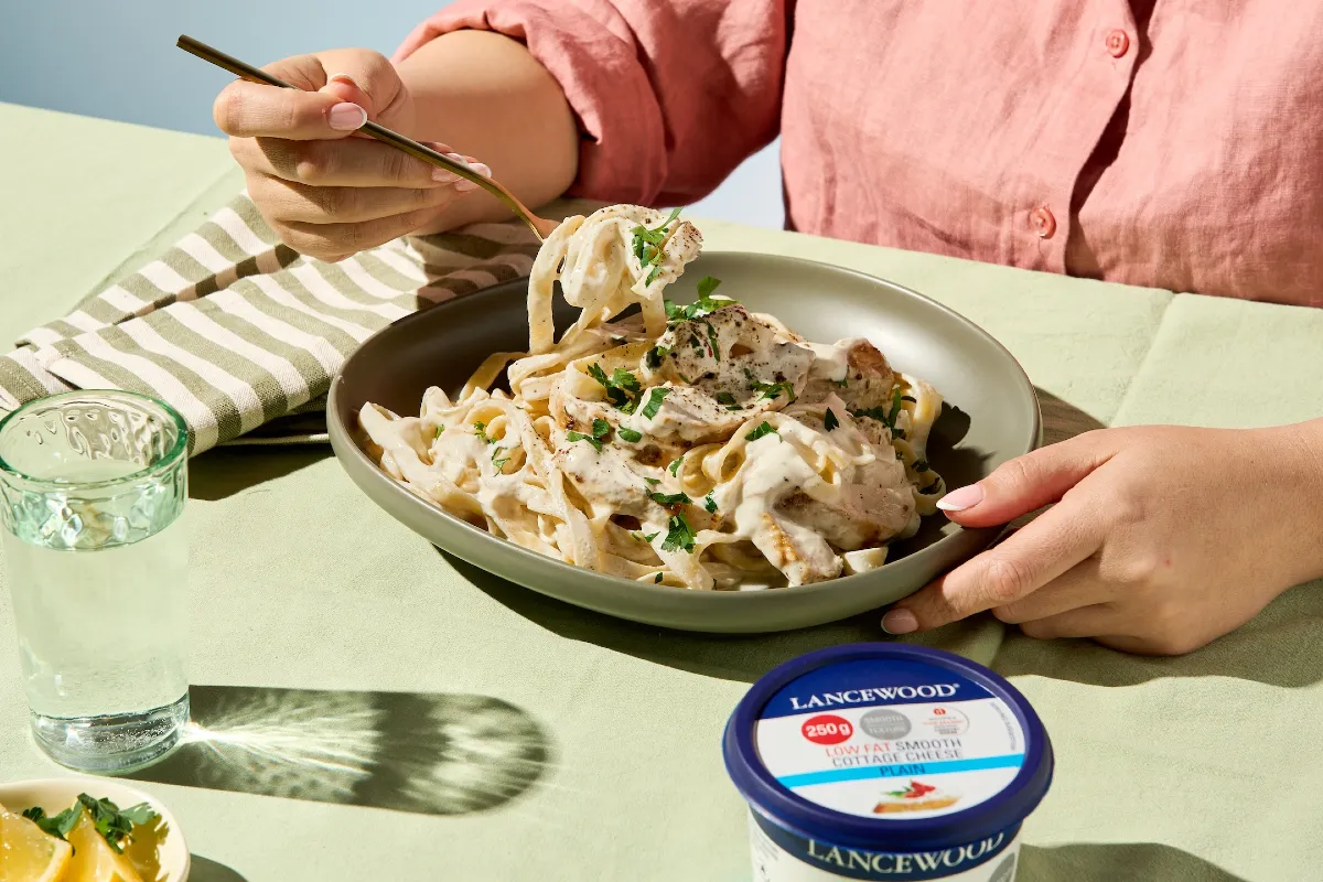 High protein chicken Alfredo Pasta, enjoyed at a table with LANCEWOOD® Cottage Cheese